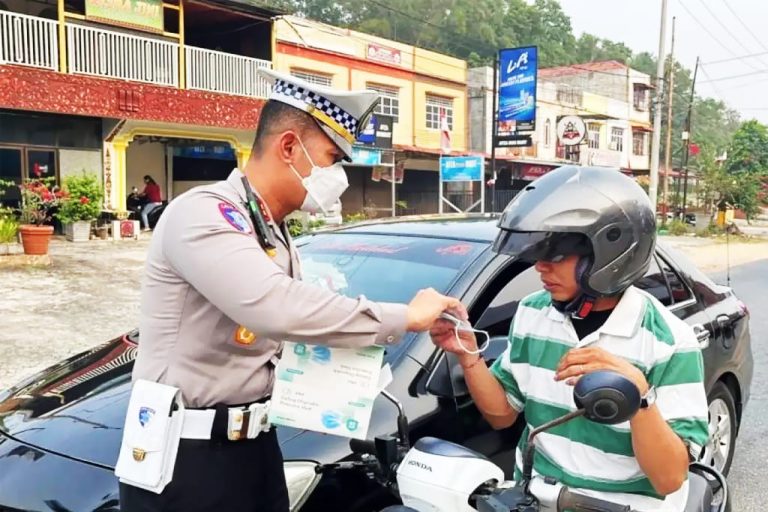 Petugas Satlantas Polres Bintan membagikan masker kepada pengendara di tengah kondisi kabut asap yang mengganggu jarak pandang di sejumlah ruas jalan Bintan, Selasa (15/9/2026)