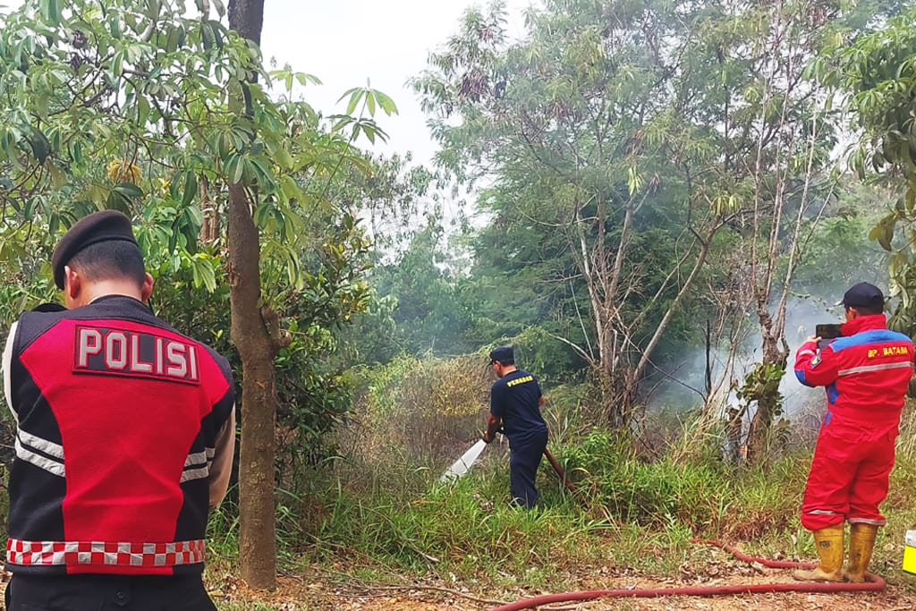Petugas pemadam kebakaran BP Batam bersama personel Polsek Nongsa memadamkan kebakaran semak belukar di tepi Jalan Sambau, Kecamatan Nongsa, Batam, Kepri, Selasa (15/9/2026)